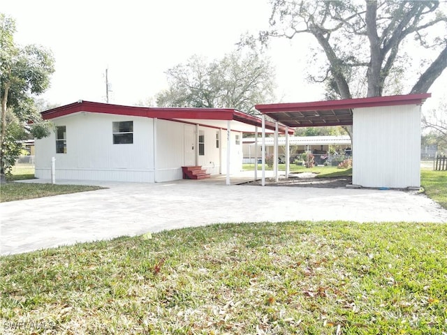 rear view of property featuring a lawn and a carport