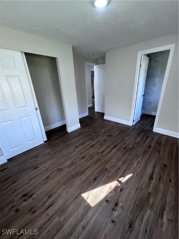 unfurnished bedroom featuring a textured ceiling, a closet, and dark hardwood / wood-style floors