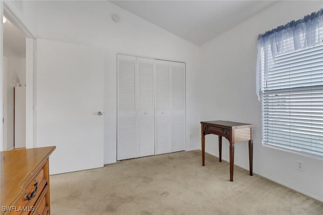 bedroom featuring light colored carpet, vaulted ceiling, and a closet