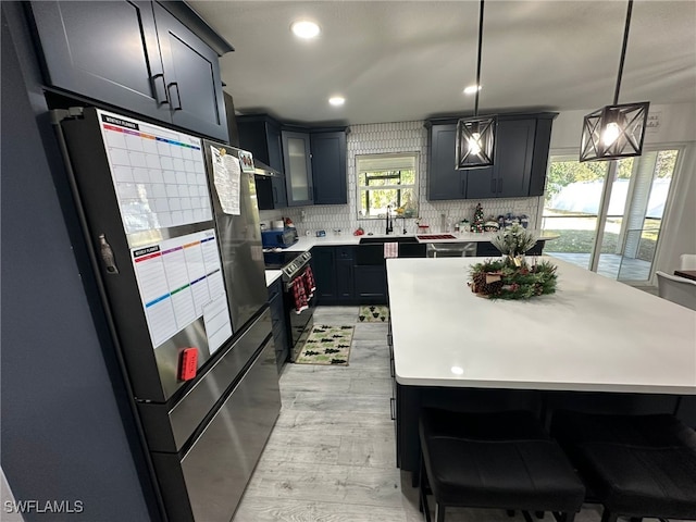 kitchen with sink, stainless steel refrigerator, backsplash, hanging light fixtures, and electric range