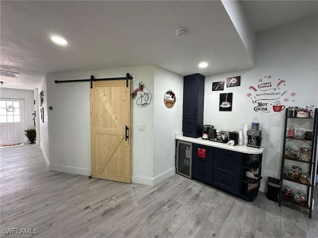 bar featuring light wood-type flooring and a barn door