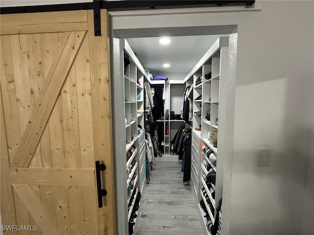 walk in closet with light hardwood / wood-style floors and a barn door