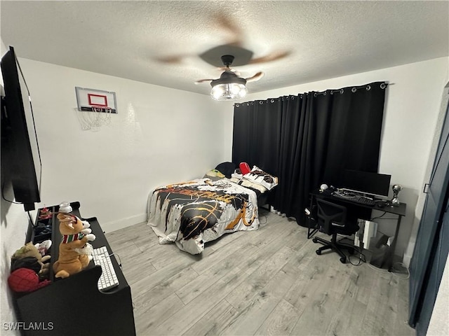 bedroom with a textured ceiling, ceiling fan, and light hardwood / wood-style floors