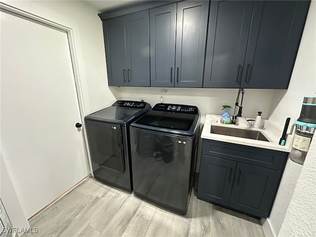 laundry room featuring cabinets, separate washer and dryer, light hardwood / wood-style flooring, and sink