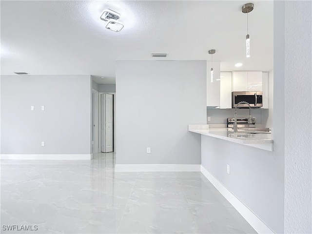 kitchen with stainless steel appliances, kitchen peninsula, a textured ceiling, white cabinets, and decorative light fixtures