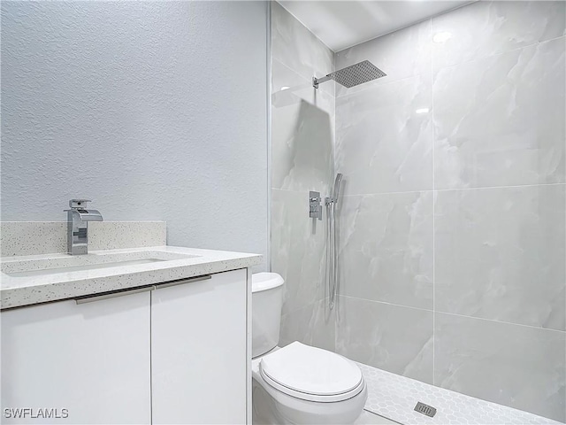 bathroom with toilet, vanity, and tiled shower