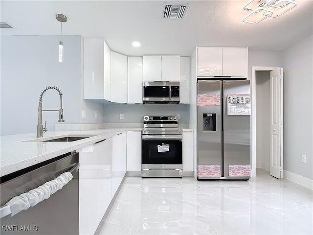 kitchen featuring sink, decorative light fixtures, white cabinets, light stone counters, and appliances with stainless steel finishes