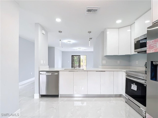 kitchen featuring kitchen peninsula, pendant lighting, white cabinetry, appliances with stainless steel finishes, and sink