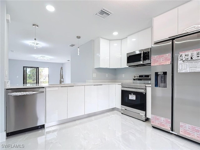 kitchen featuring kitchen peninsula, pendant lighting, stainless steel appliances, white cabinetry, and sink