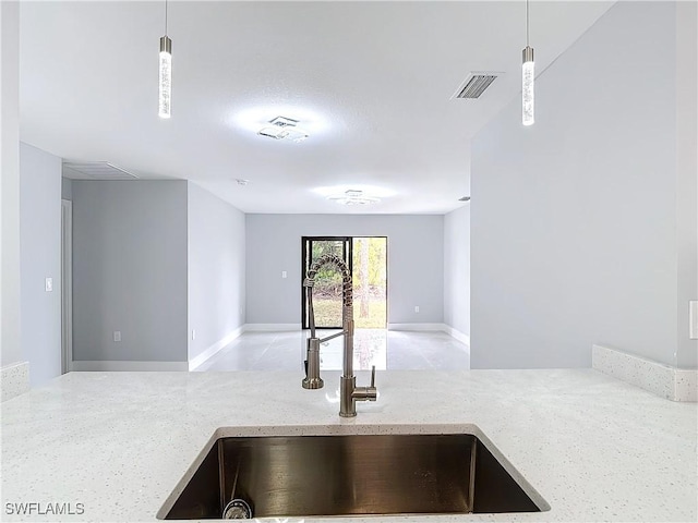 kitchen with sink, pendant lighting, and light stone counters