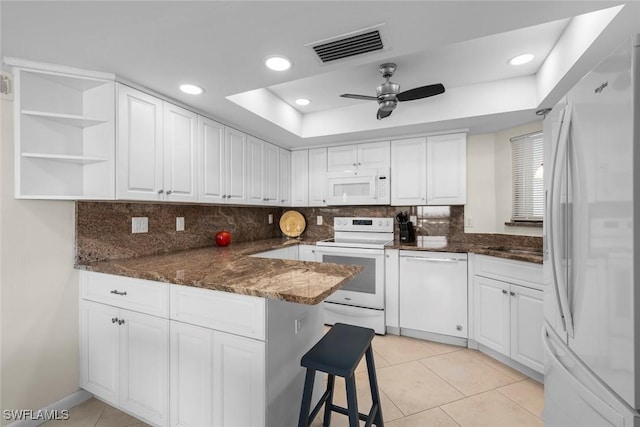 kitchen featuring light tile patterned floors, white appliances, white cabinetry, a raised ceiling, and kitchen peninsula