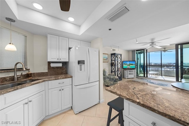 kitchen featuring sink, white fridge with ice dispenser, pendant lighting, ceiling fan, and white cabinets