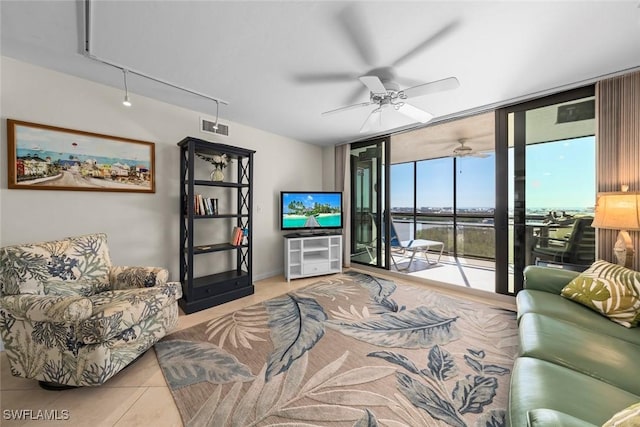 tiled living room with ceiling fan and a wall of windows