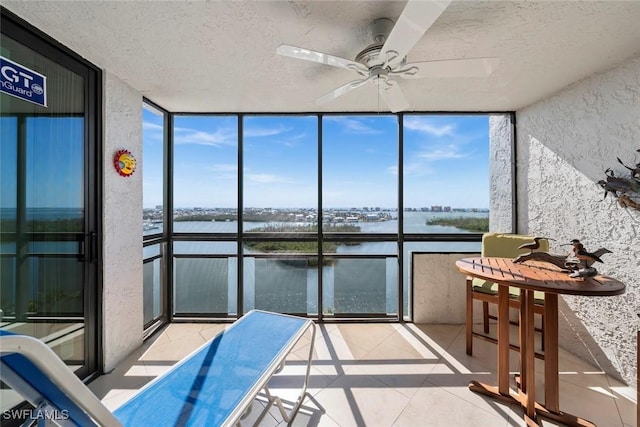 sunroom with a water view and ceiling fan