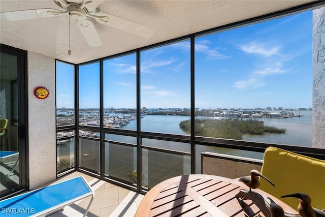 unfurnished sunroom featuring ceiling fan and a water view