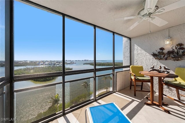 sunroom with a water view and ceiling fan