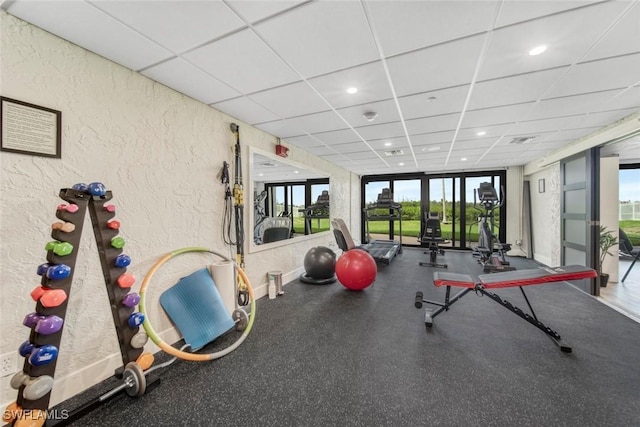 workout area with a wall of windows, a healthy amount of sunlight, and a drop ceiling