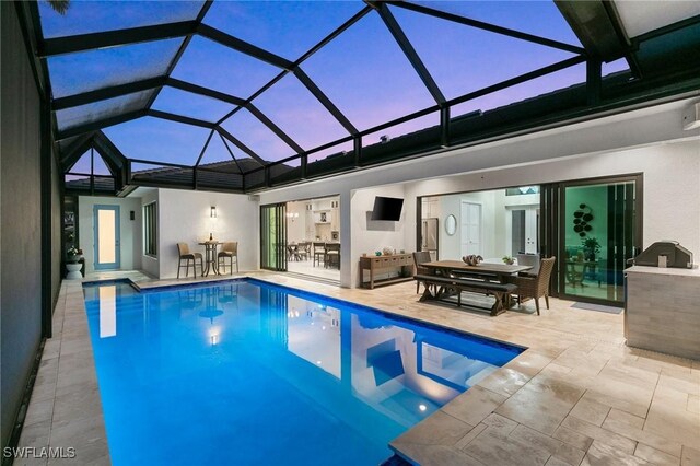 view of pool with a lanai, a patio area, and an outdoor kitchen