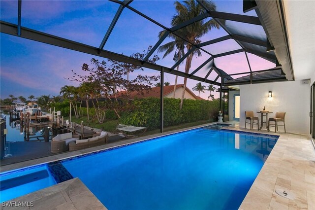 pool at dusk with a lanai, a dock, a water view, and a patio