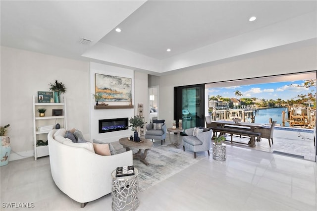 living room with a water view and a tray ceiling