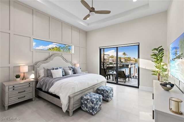 bedroom featuring ceiling fan, access to exterior, and a tray ceiling