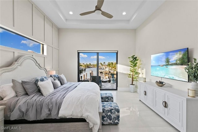 bedroom with ceiling fan, access to exterior, multiple windows, and a tray ceiling