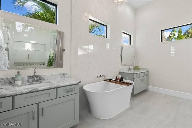 100 Templewood Ct, Marco Island, FL 34145 - bathroom with two vanities, a freestanding bath, baseboards, a towering ceiling, and a shower