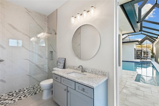 bathroom with toilet, vanity, and a tile shower