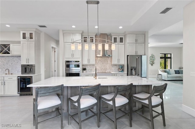 100 Templewood Ct, Marco Island, FL 34145 - kitchen with stainless steel appliances, wine cooler, tasteful backsplash, wall chimney range hood, and white cabinetry