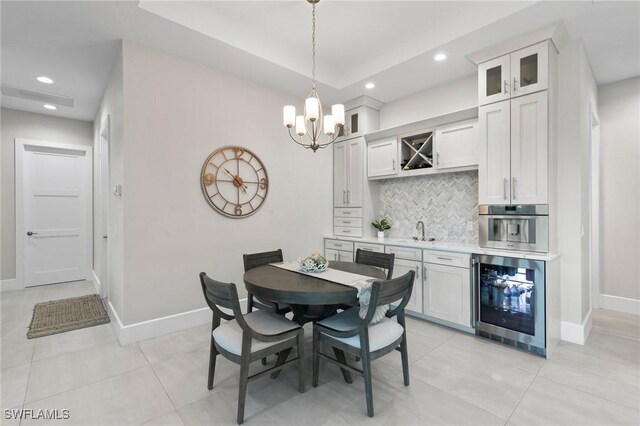 tiled dining area featuring an inviting chandelier, beverage cooler, and sink