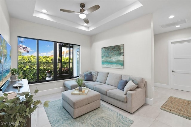 living room featuring ceiling fan, light tile patterned floors, and a tray ceiling