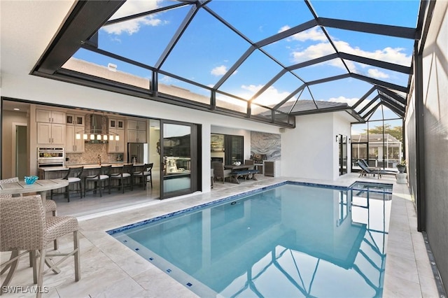 view of swimming pool featuring a patio area, a lanai, and a wet bar