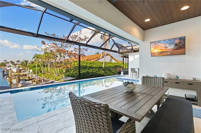 view of pool with a water view, a patio, and glass enclosure