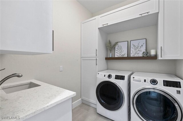 laundry room with washing machine and dryer, cabinets, and sink