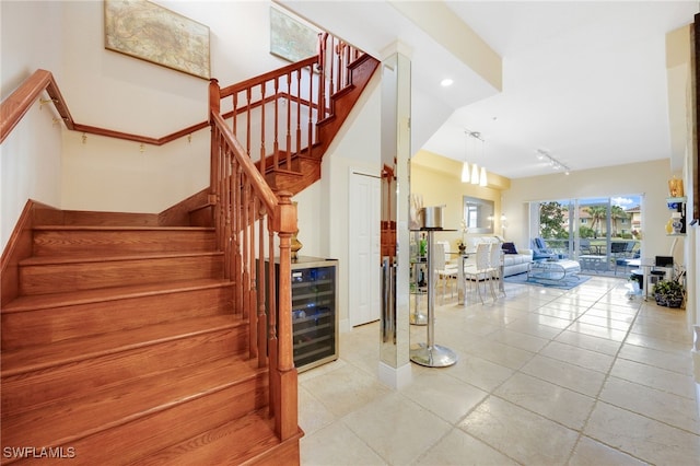 staircase featuring track lighting, beverage cooler, and tile patterned floors