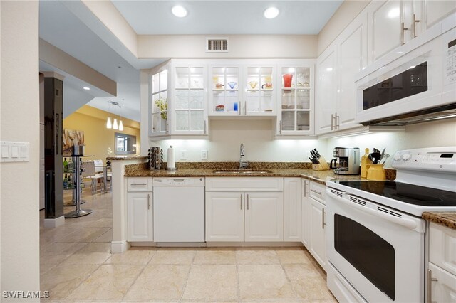 kitchen with white appliances, white cabinets, dark stone countertops, sink, and kitchen peninsula