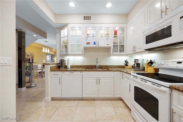 kitchen with white appliances, dark stone countertops, sink, white cabinetry, and kitchen peninsula