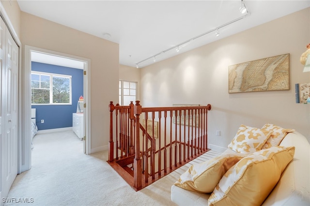 hall featuring rail lighting and light colored carpet