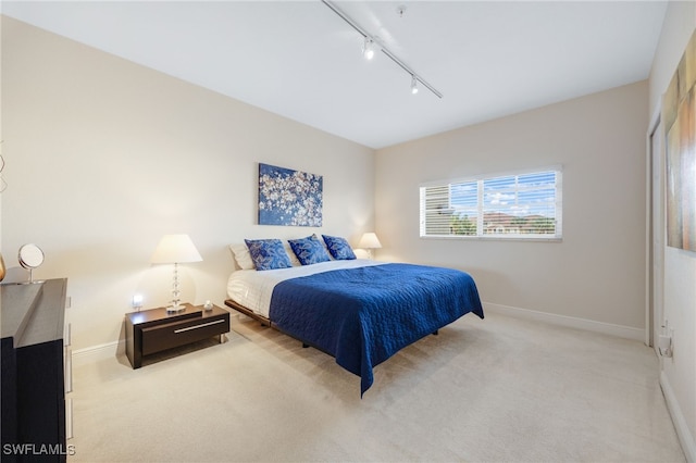 bedroom featuring track lighting and light colored carpet