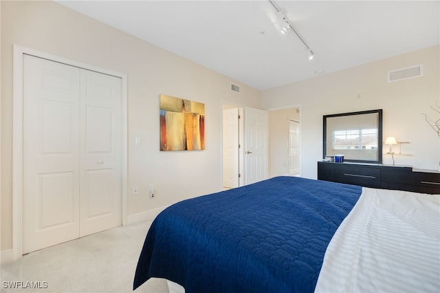 bedroom featuring light carpet, a closet, and track lighting