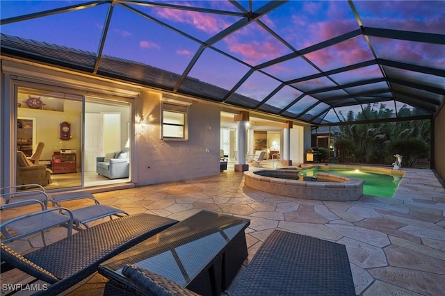 patio terrace at dusk featuring a lanai and a pool with hot tub