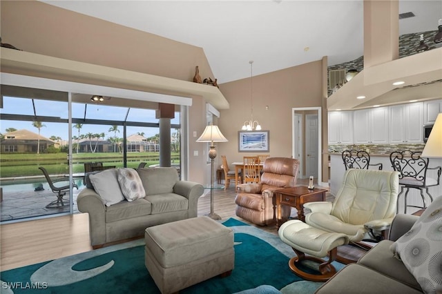 living room featuring high vaulted ceiling, light wood-type flooring, and a chandelier