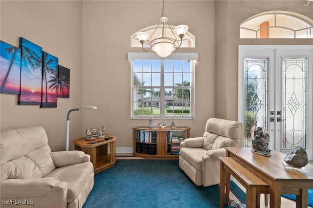 sitting room with dark carpet, french doors, and an inviting chandelier