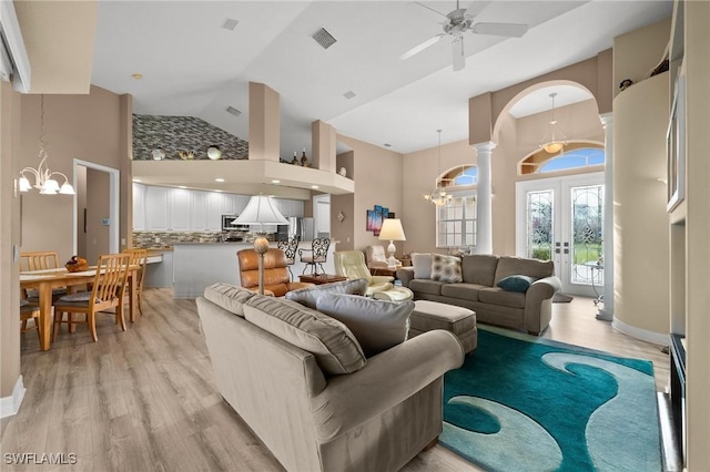 living room with high vaulted ceiling, french doors, ceiling fan with notable chandelier, and light hardwood / wood-style floors