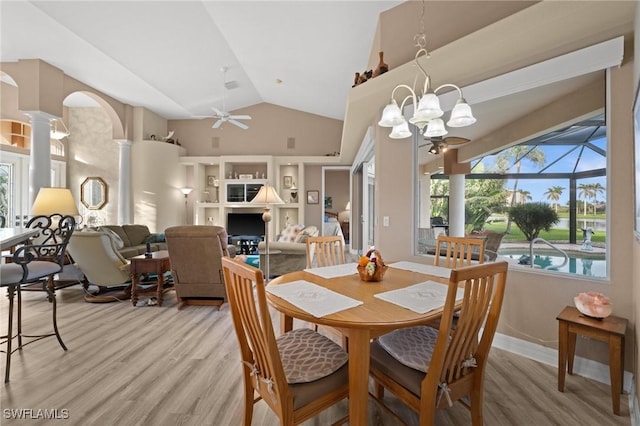 dining space with ceiling fan with notable chandelier, hardwood / wood-style flooring, ornate columns, and vaulted ceiling