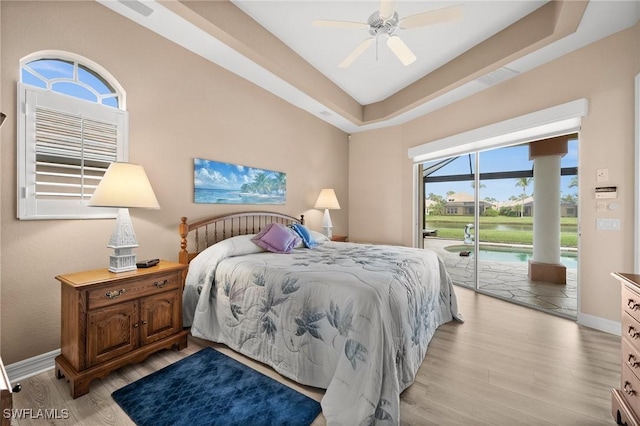 bedroom with ceiling fan, light hardwood / wood-style flooring, access to outside, and a raised ceiling