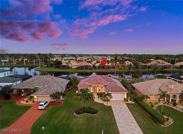 aerial view at dusk featuring a water view