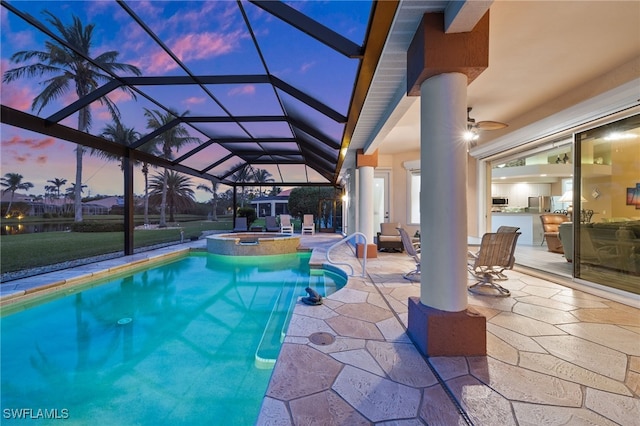 pool at dusk with a lanai, ceiling fan, a patio area, area for grilling, and an in ground hot tub