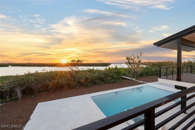 pool at dusk featuring a water view and a patio area