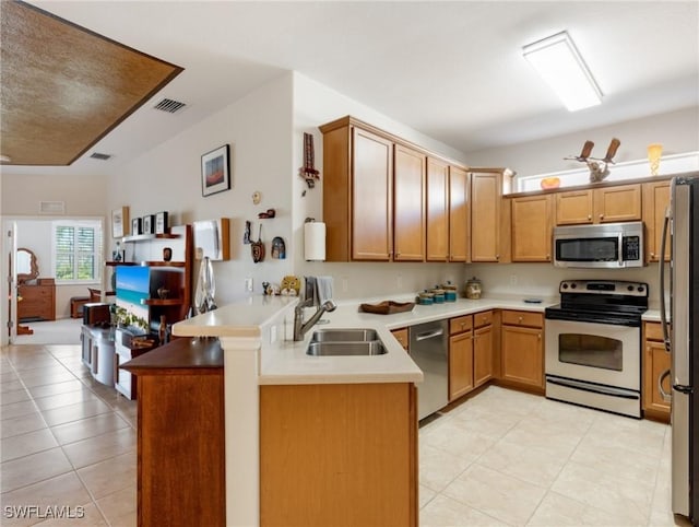 kitchen with kitchen peninsula, appliances with stainless steel finishes, light tile patterned floors, and sink